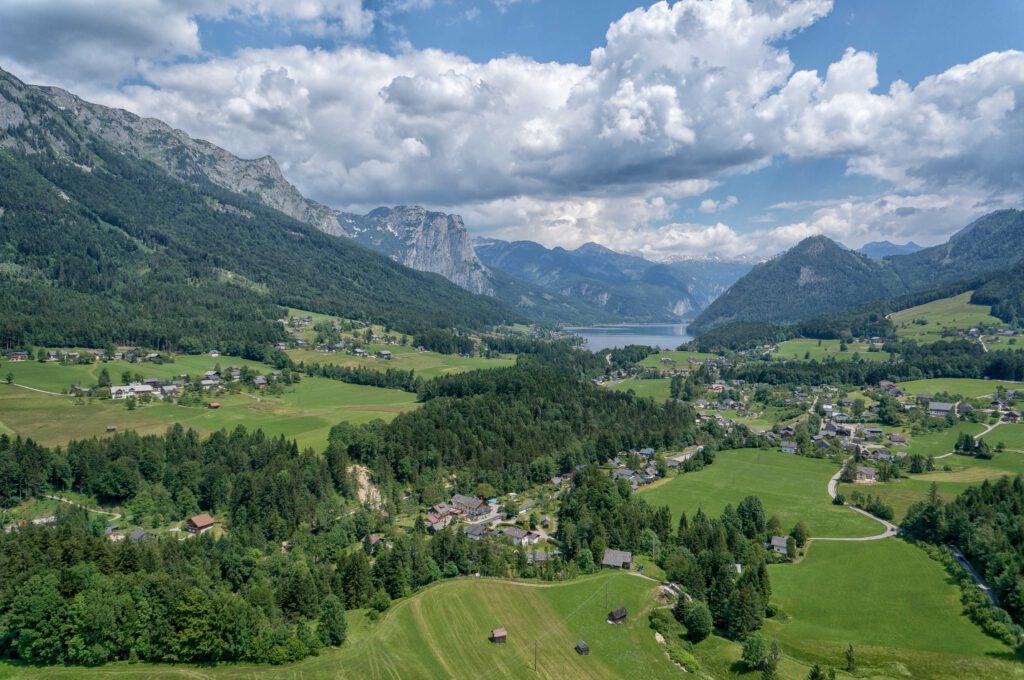 Landschaftsaufnahme des Bad Aussee mit Bergen, Wäldern und Wiesen in der Umgebung.