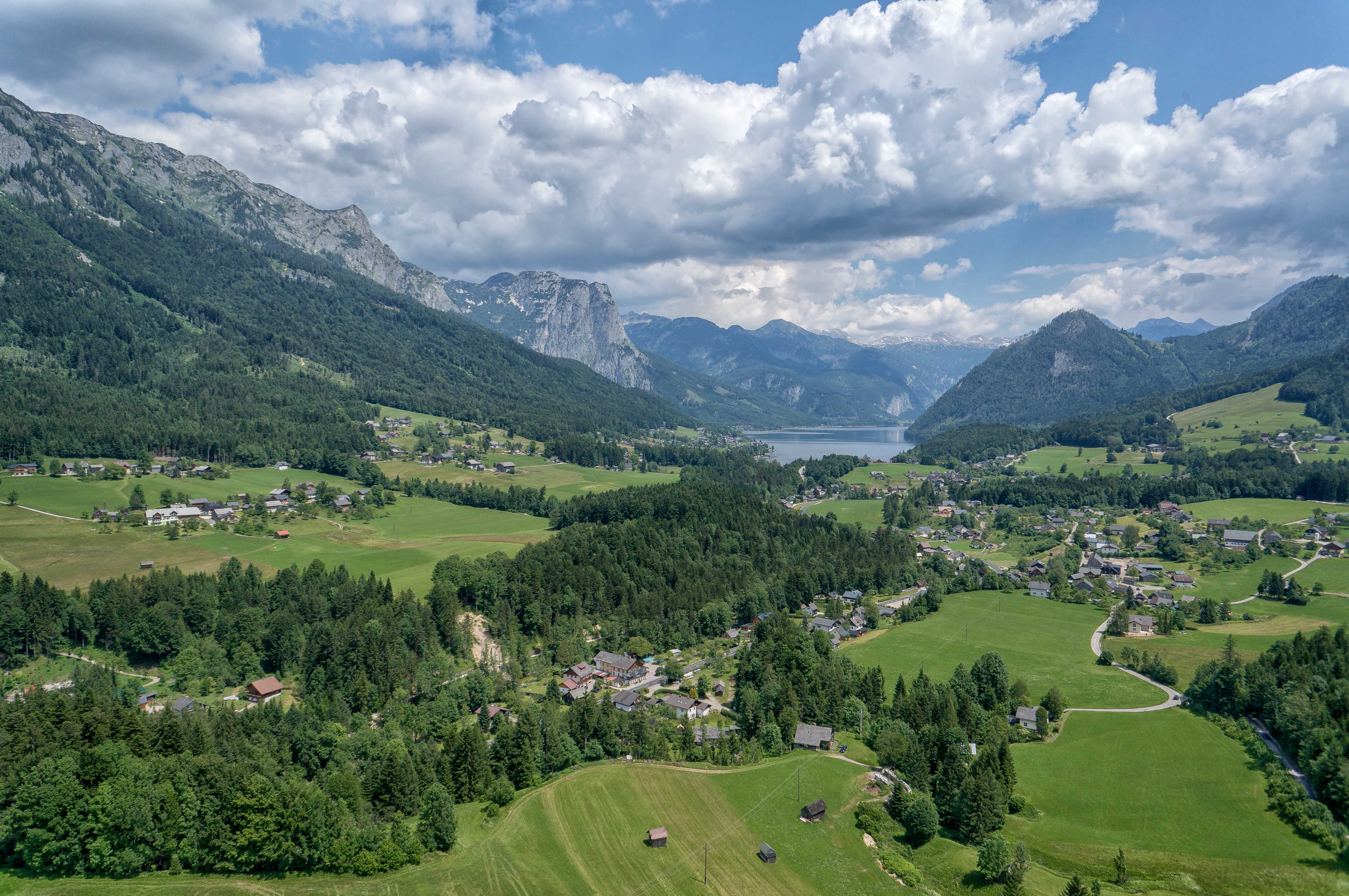 Landschaftsaufnahme des Bad Aussee mit Bergen, Wäldern und Wiesen in der Umgebung.