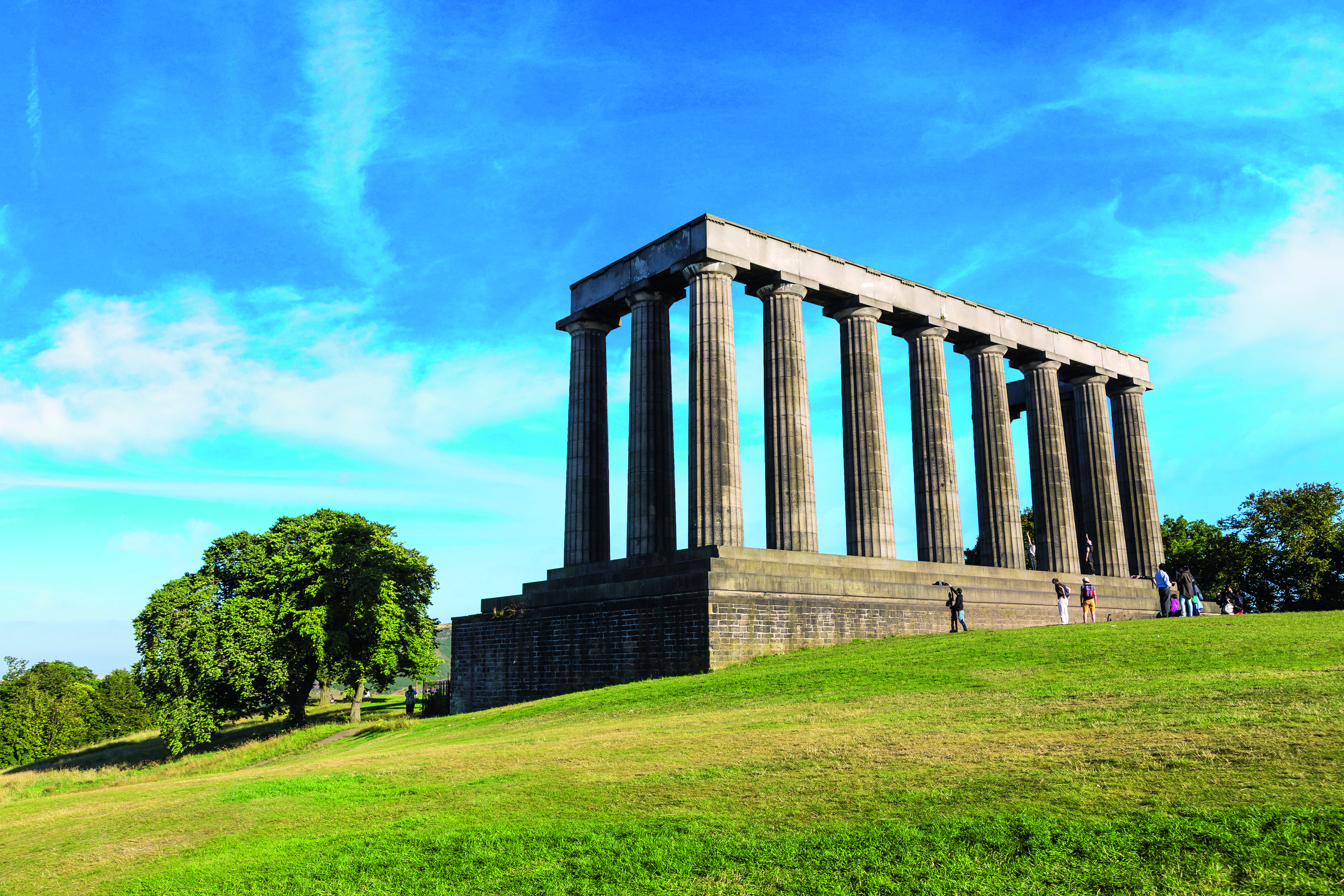 Das National Monument auf dem Calton Hill in Edinburgh mit Säulenstruktur und grünem Rasen im Vordergrund.