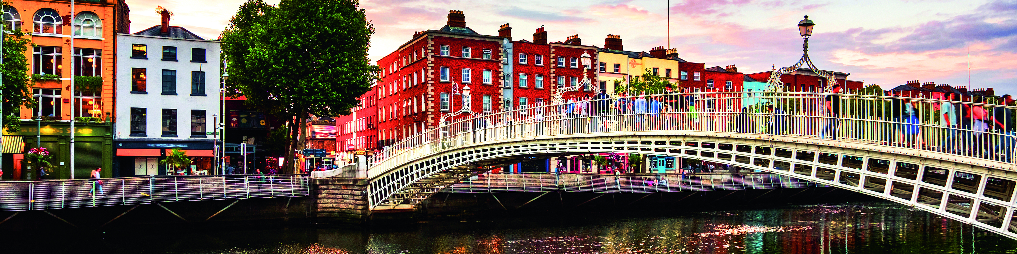 Halfpenny Bridge in Dublin mit farbenfrohen Gebäuden im Hintergrund und reflektierendem Wasser.