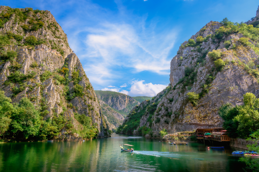 Blick auf eine ruhige Schlucht mit Wasser und Boot, umgeben von steilen Felsen und Bäumen.