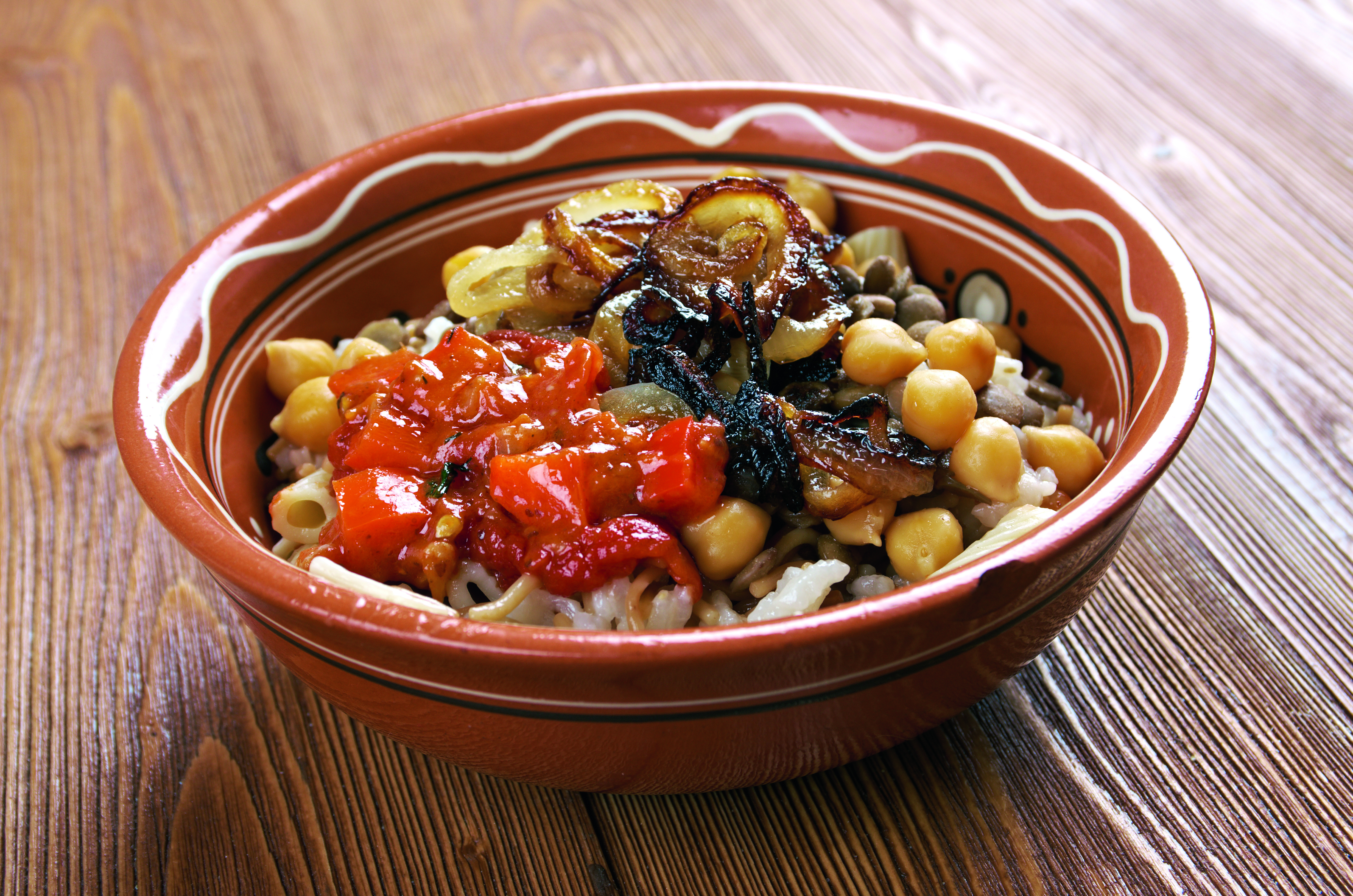 Schüssel mit Koshari, einem ägyptischen Gericht aus Reis, Linsen, Kichererbsen und Tomatensauce.