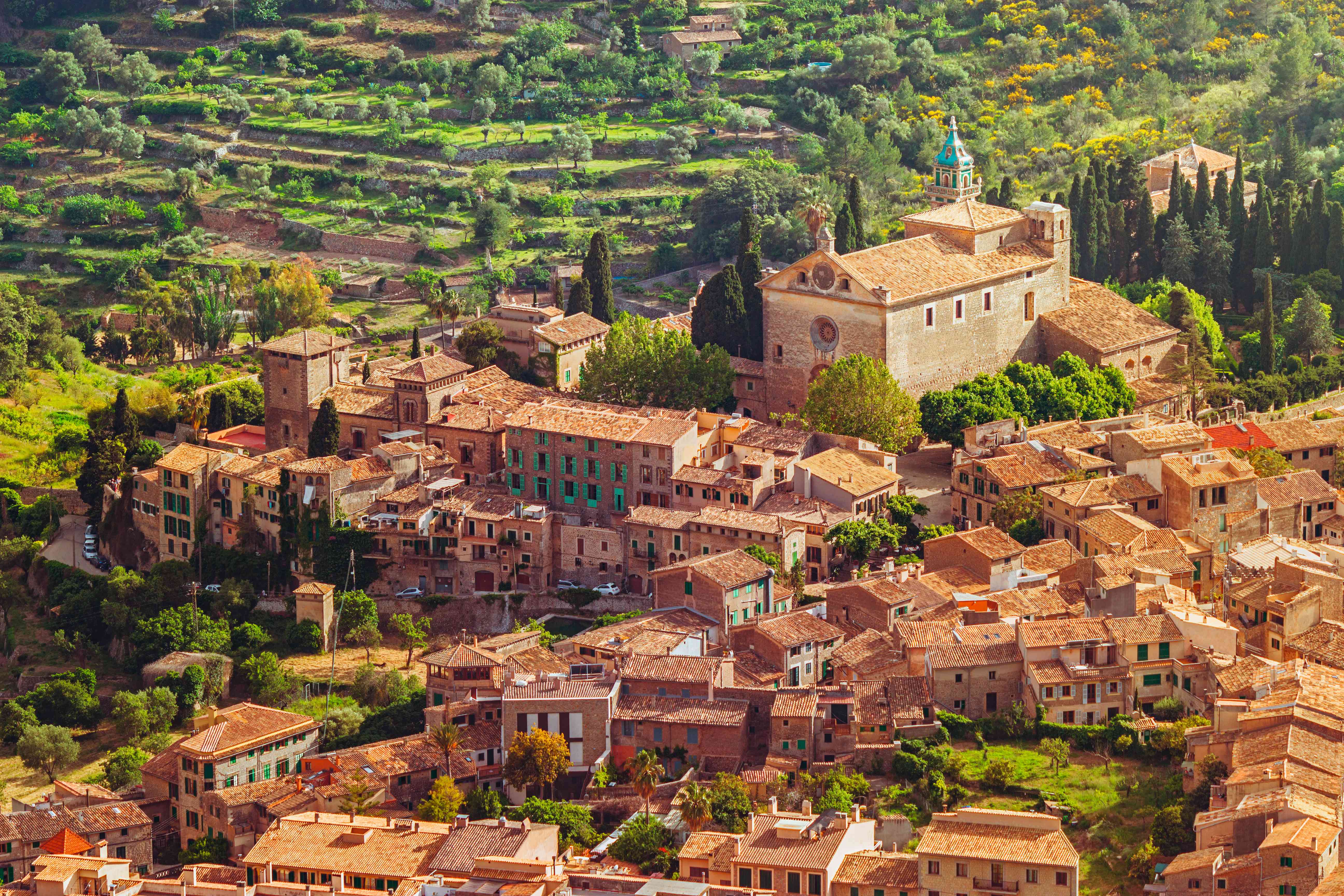 Luftaufnahme des Kartäuserklosters in Valldemossa, Mallorca, umgeben von grünen Feldern und traditioneller Architektur.