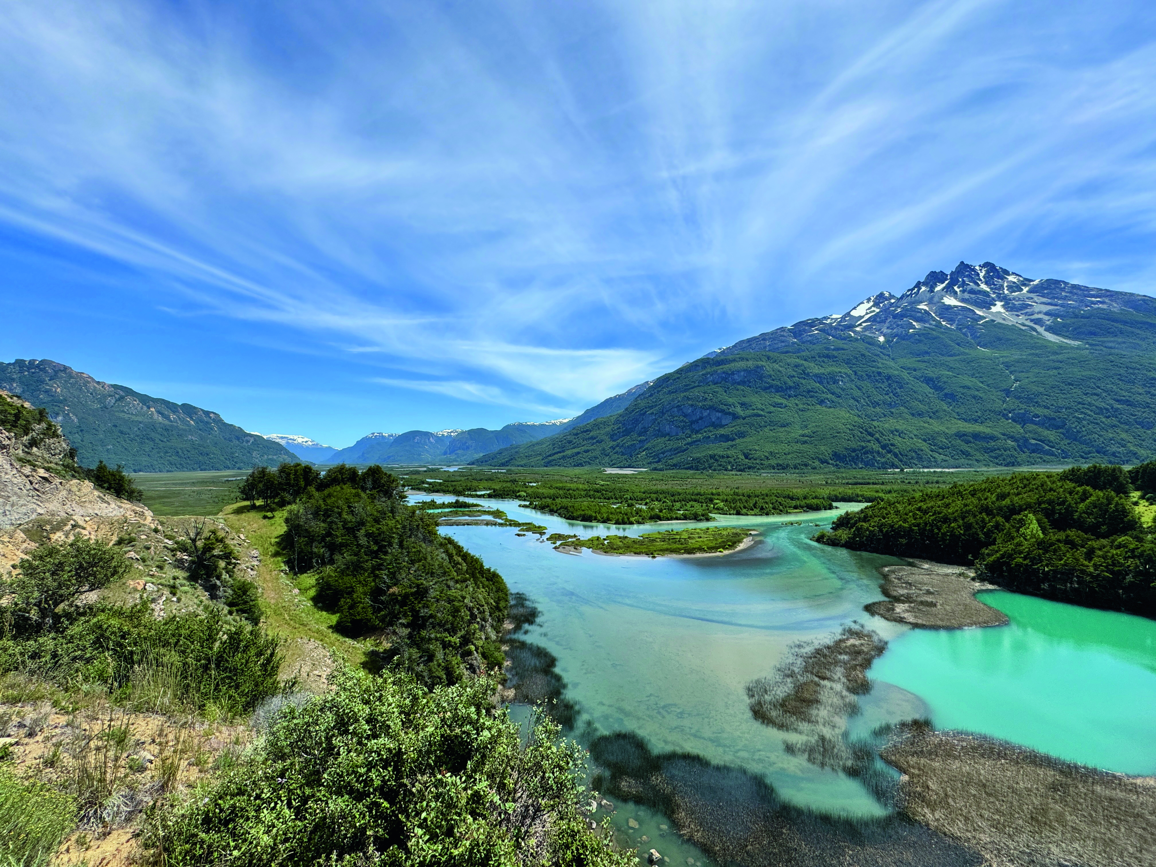 Blick auf einen Fluss mit türkisfarbenem Wasser und umgebenden Bergen in einer natürlichen Landschaft.