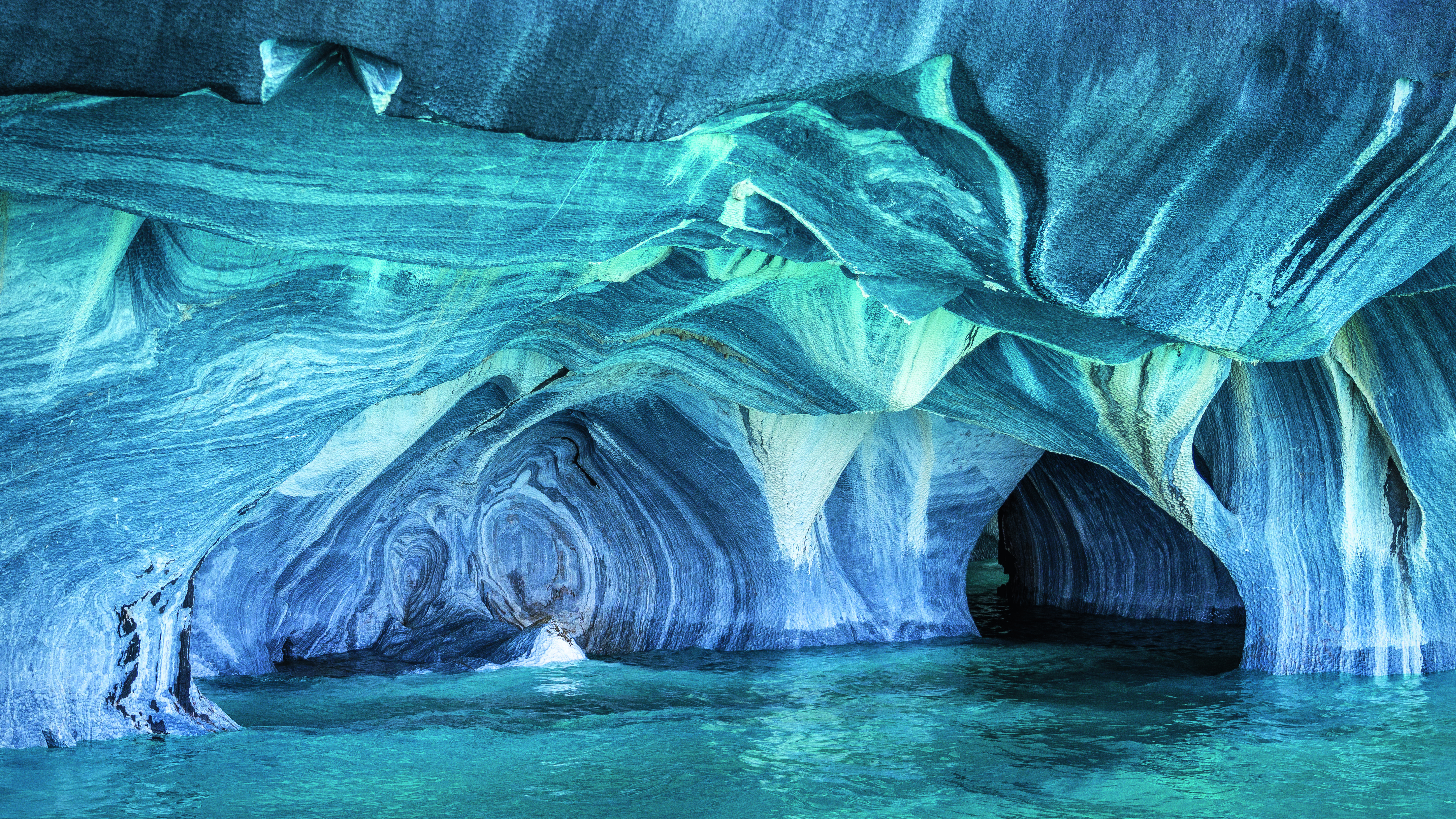 Blaue Marmorhöhlen mit geschwungenen, marmorierten Wänden und klarem Wasser im Inneren.