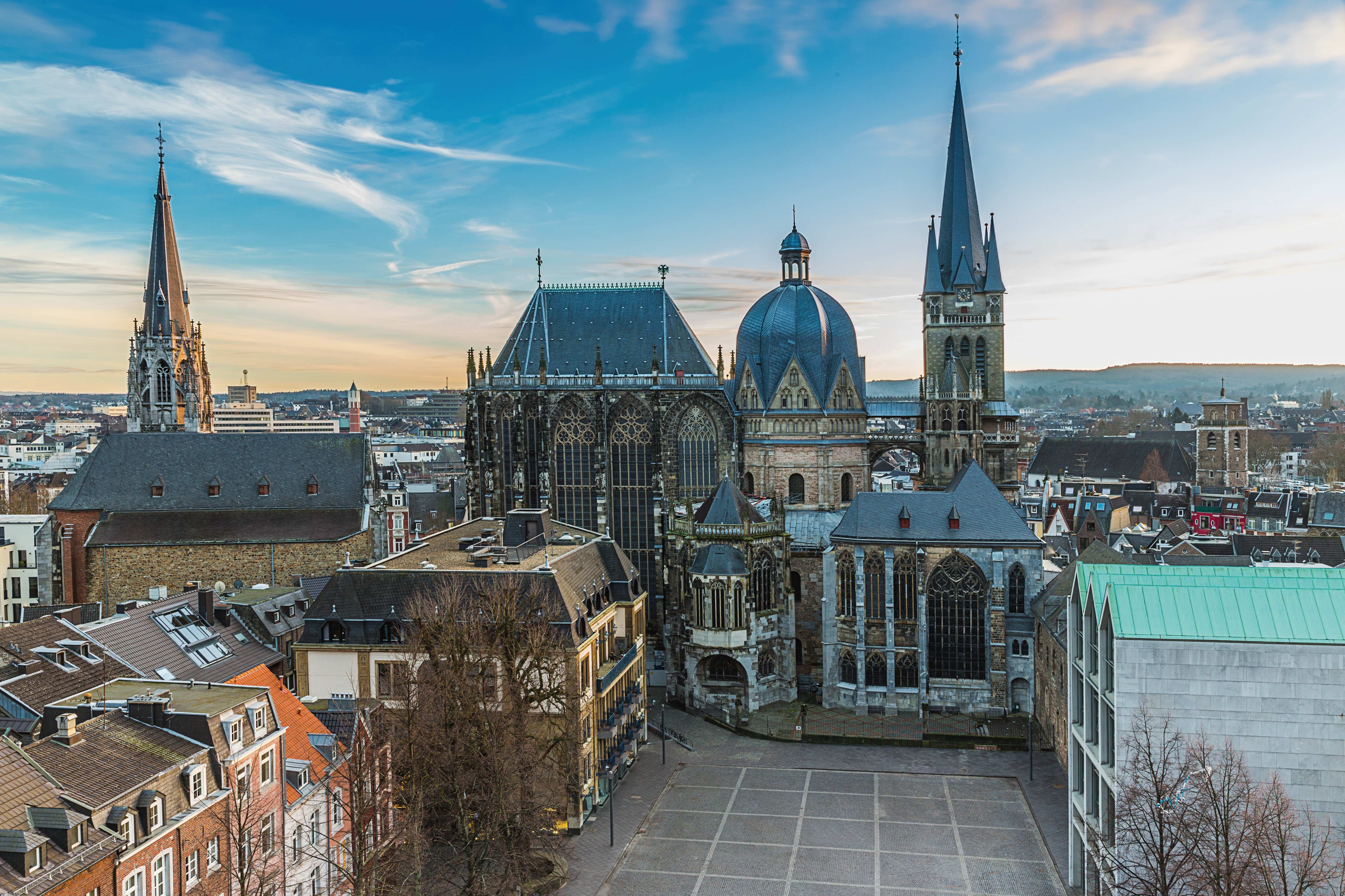 Aachener Dom mit markanten Türmen und Kuppel, umgeben von historischen Gebäuden in Aachen.