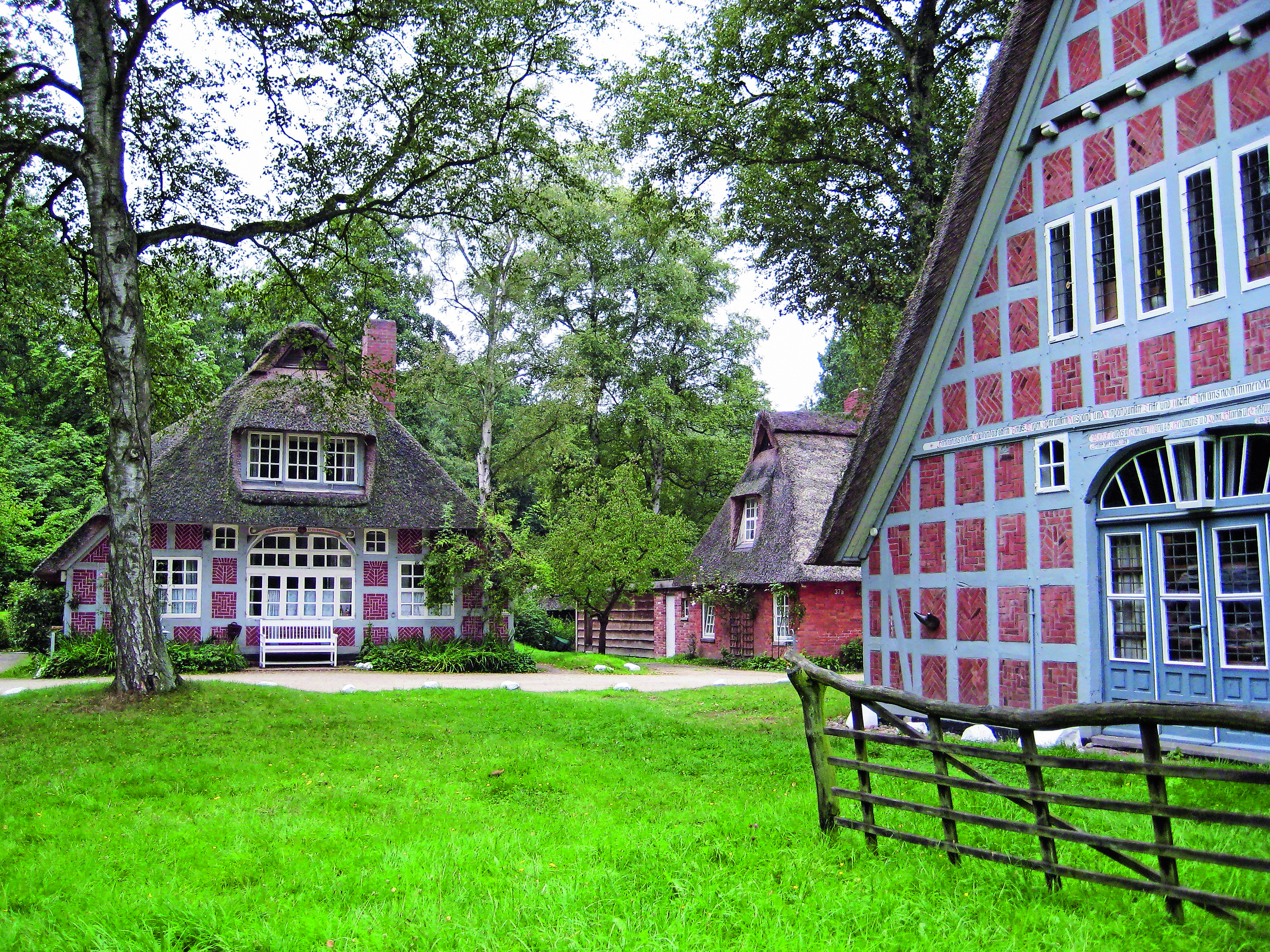 Traditionelles Fachwerkhaus mit Reetdach in einer grünen Umgebung.