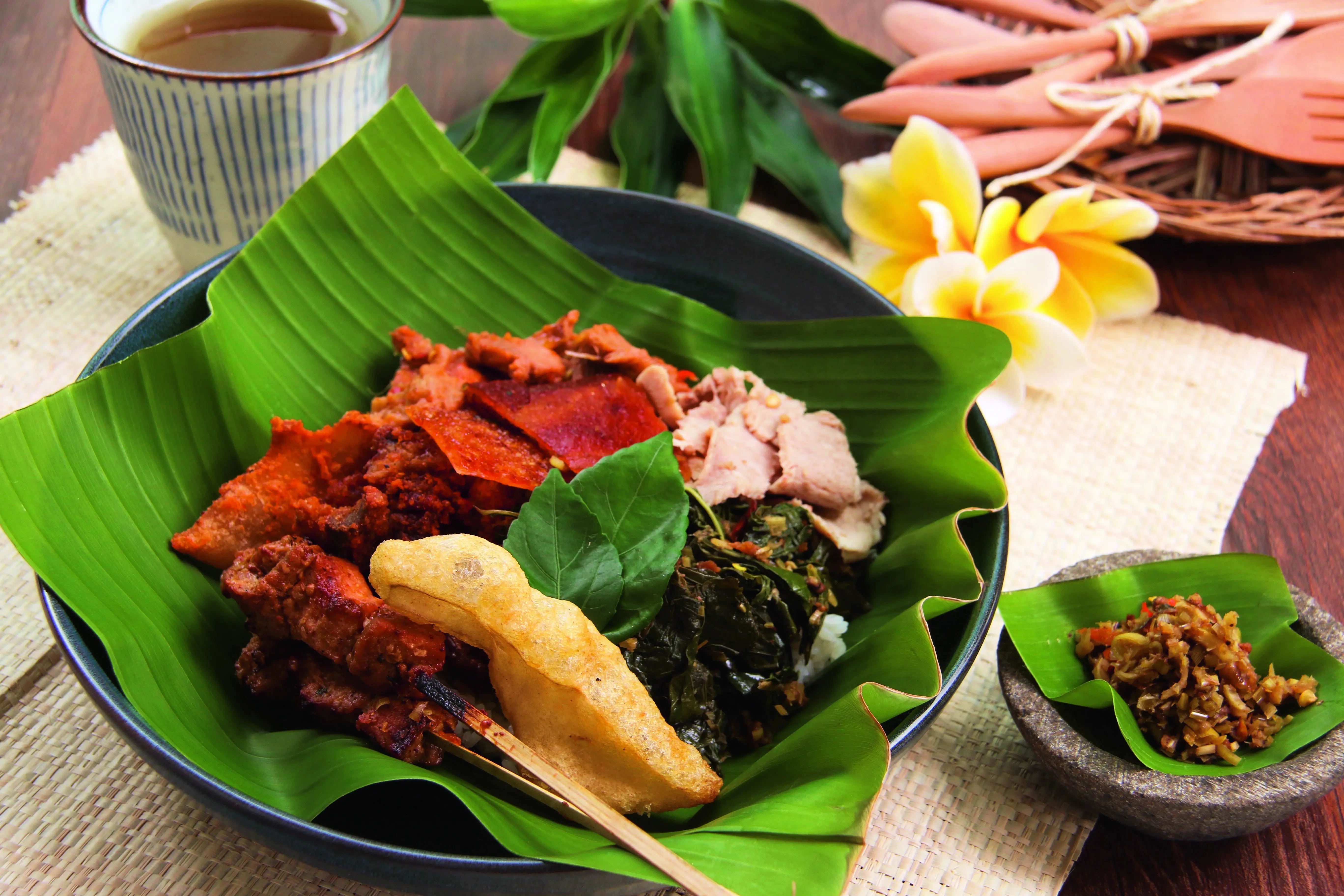 Traditionelles balinesisches Gericht Nasi Campur mit verschiedenen Fleischsorten und Beilagen auf einem Teller.