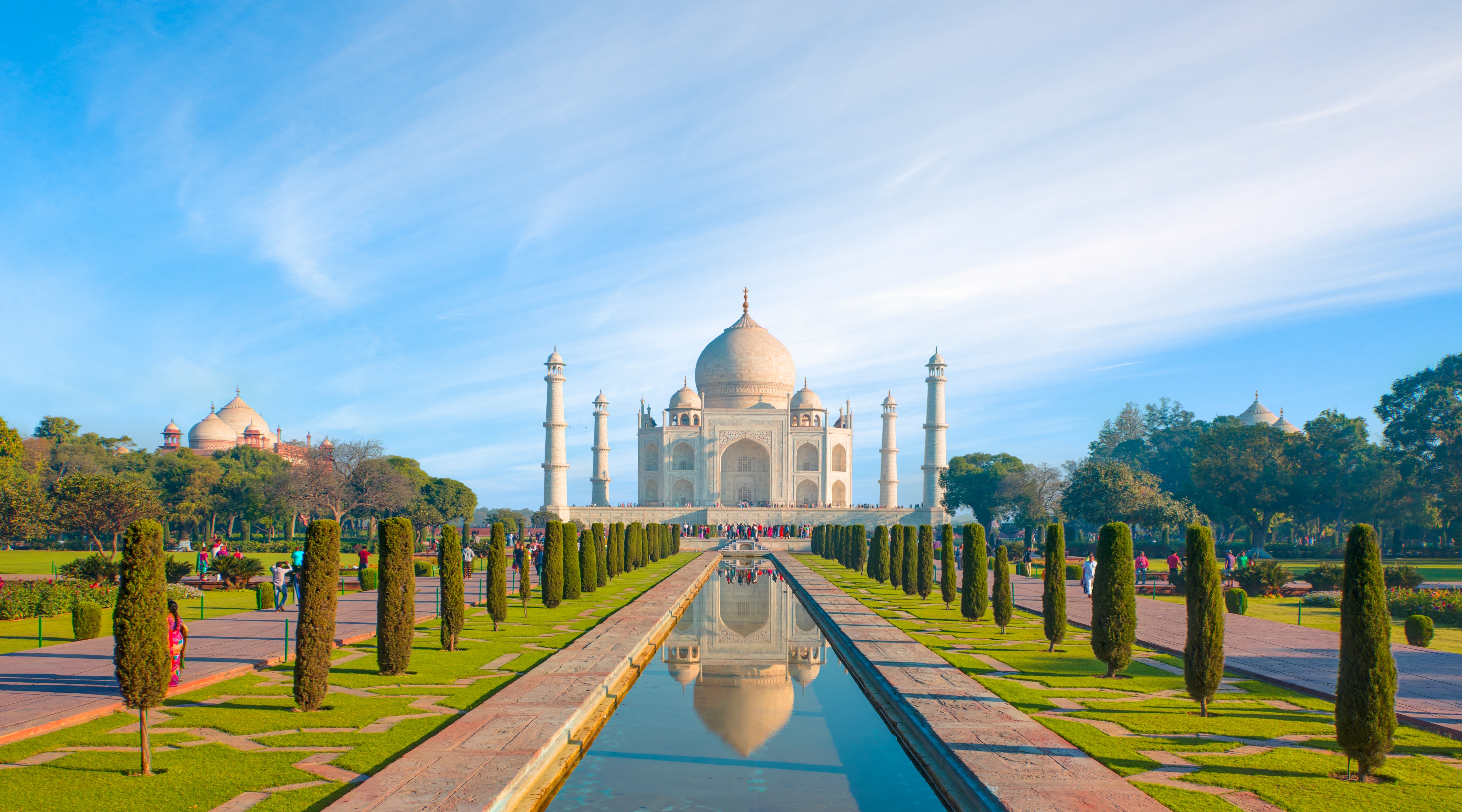 Taj Mahal in Indien mit einem klaren Himmel und einem Wasserbecken im Vordergrund.
