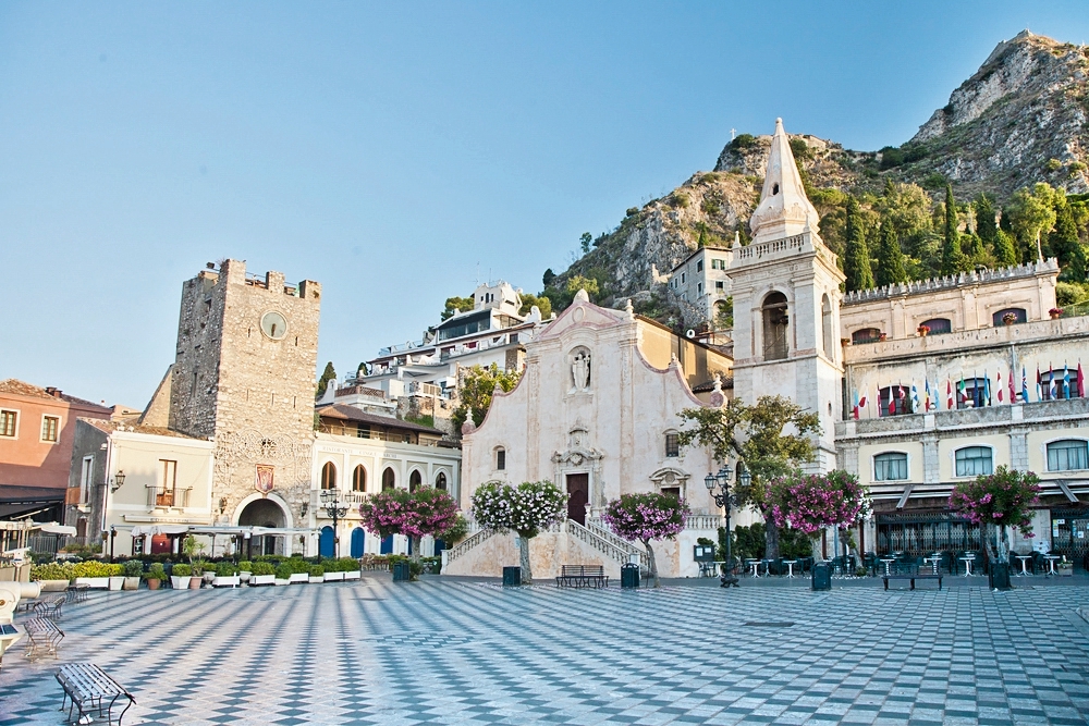 Platz in Taormina mit historischen Gebäuden und einer Kirche im Hintergrund.