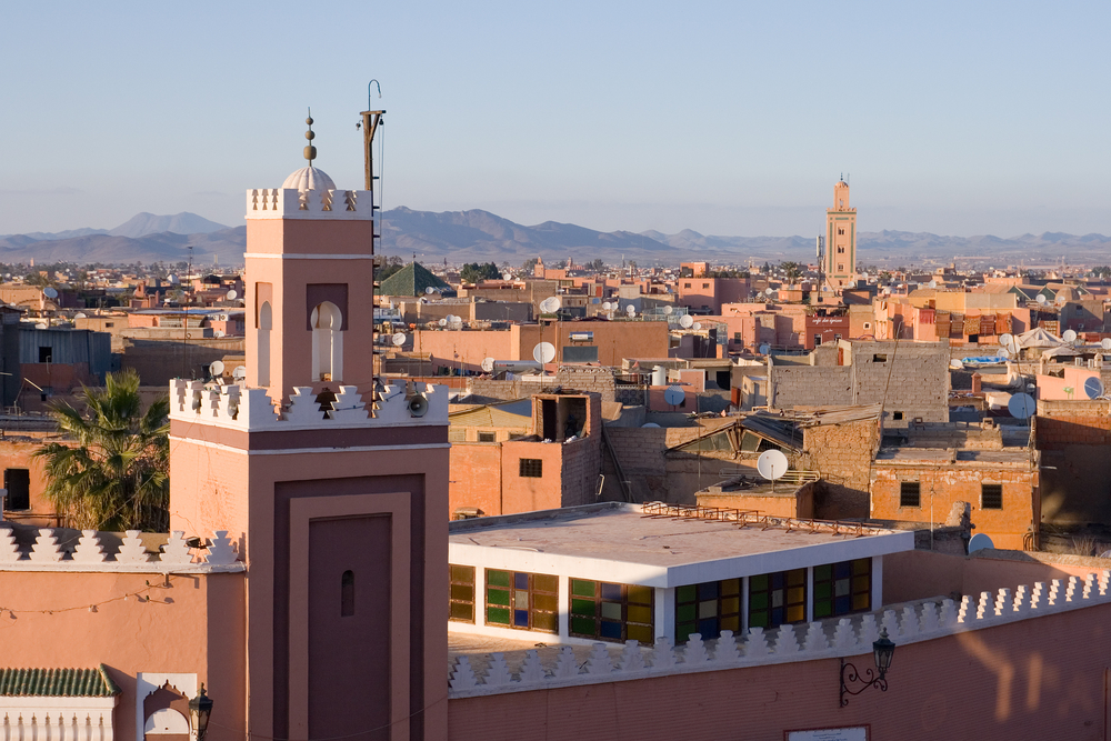 Blick auf die Stadt Marrakesch mit Stadtmauer und Gebäuden im Vordergrund.