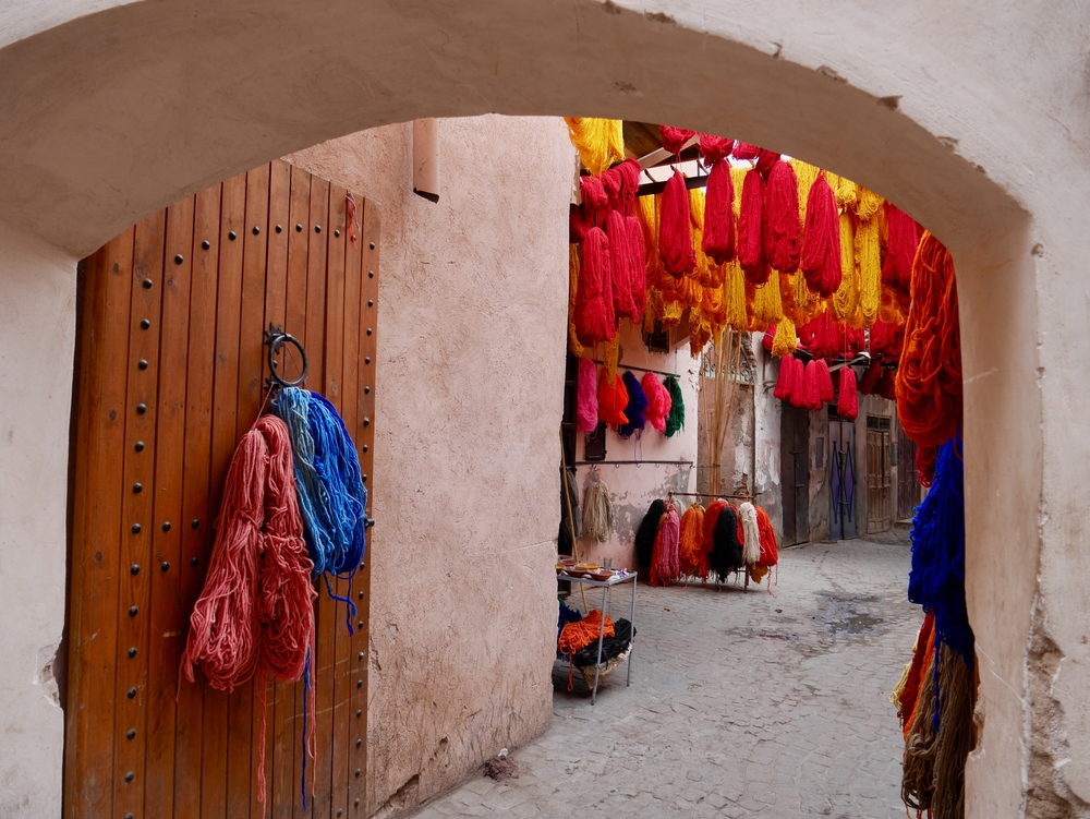 Bunte Wollfäden in einem Souk in Marrakesch, aufgehängt über einem Durchgang.