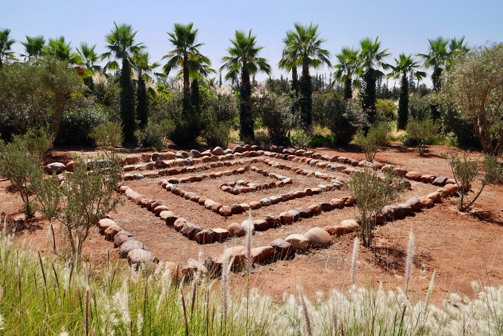 Anima Garten im Ourika Tal mit einem Steinkreis und Palmen im Hintergrund.