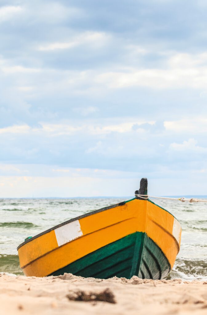 Holzboot mit gelber und grüner Lackierung am Strand der Ostsee.