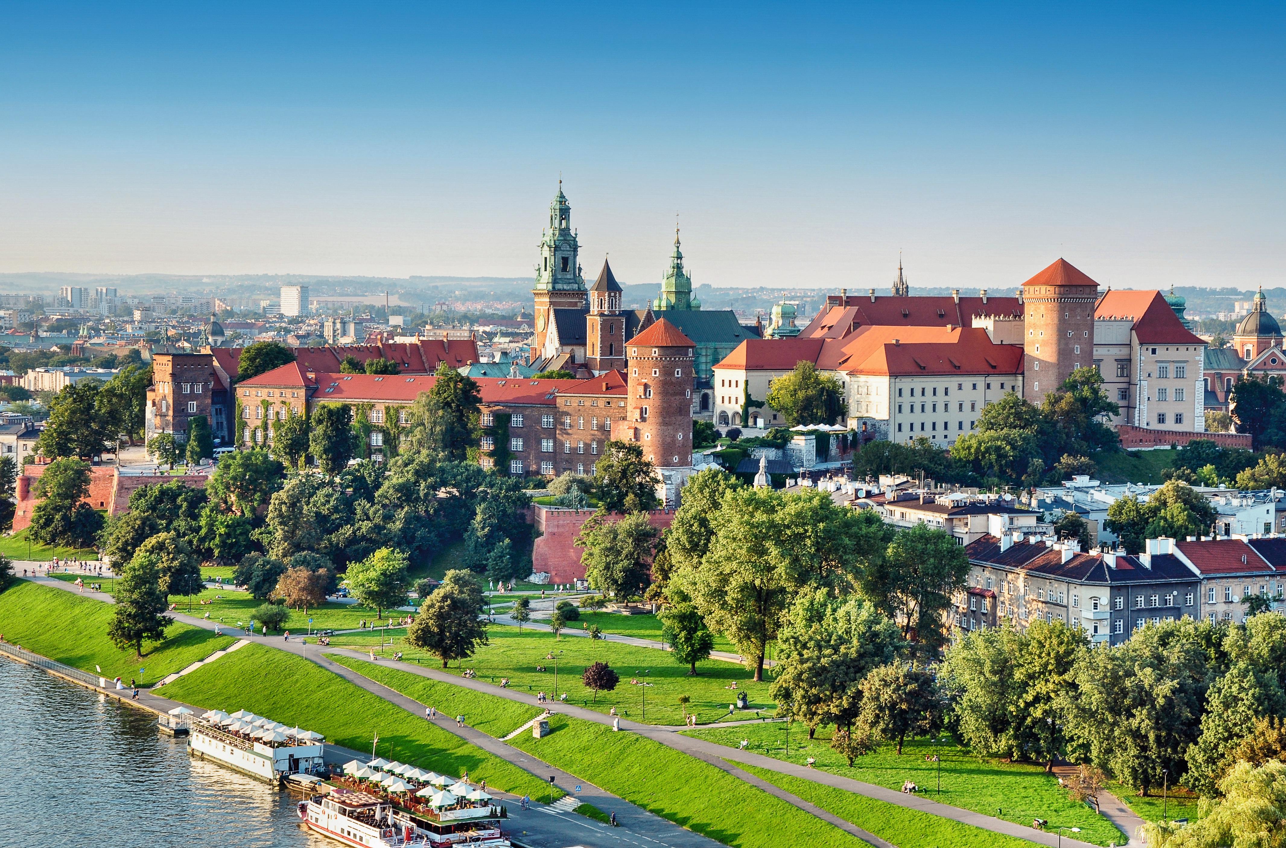 Wawel Castle in Krakau mit roten Dächern und grünen Bäumen, umgeben von einer klaren blauen Himmel.