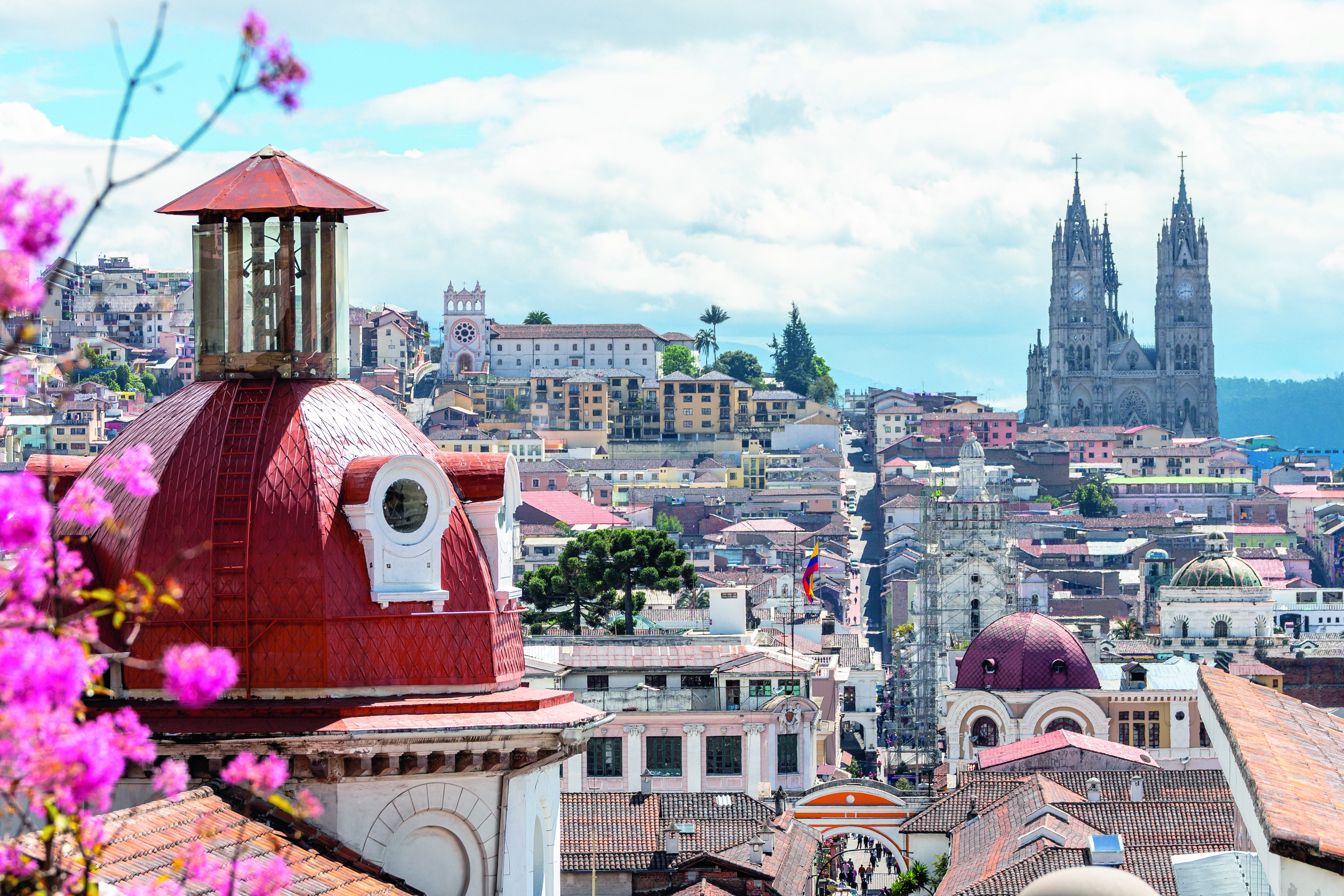 Blick auf die Altstadt von Quito mit roten Dächern und der Basilika del Voto Nacional im Hintergrund.