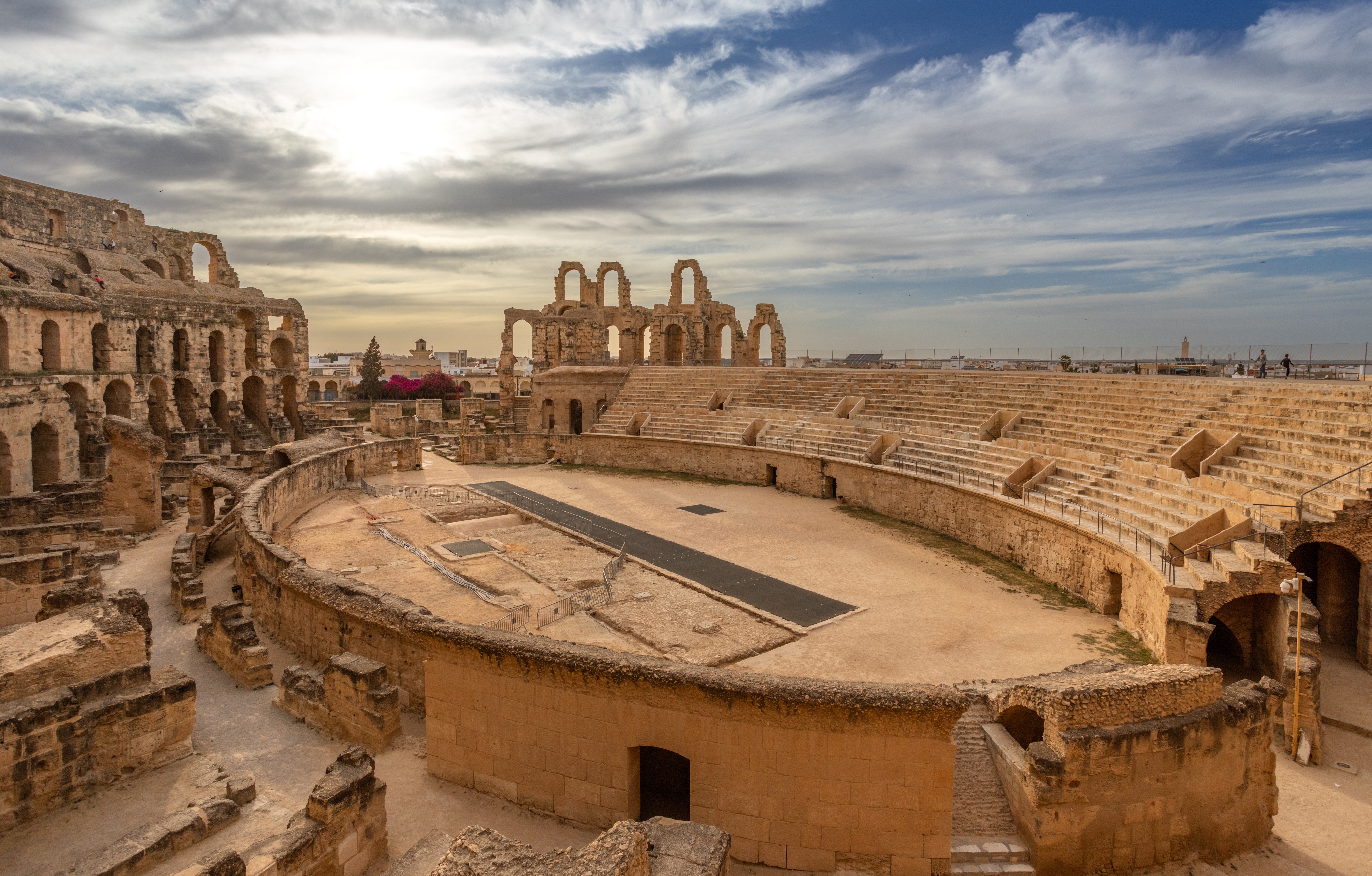 Römisches Amphitheater in El Djem mit gut erhaltenen Steinterrassen und Wolken am Himmel.
