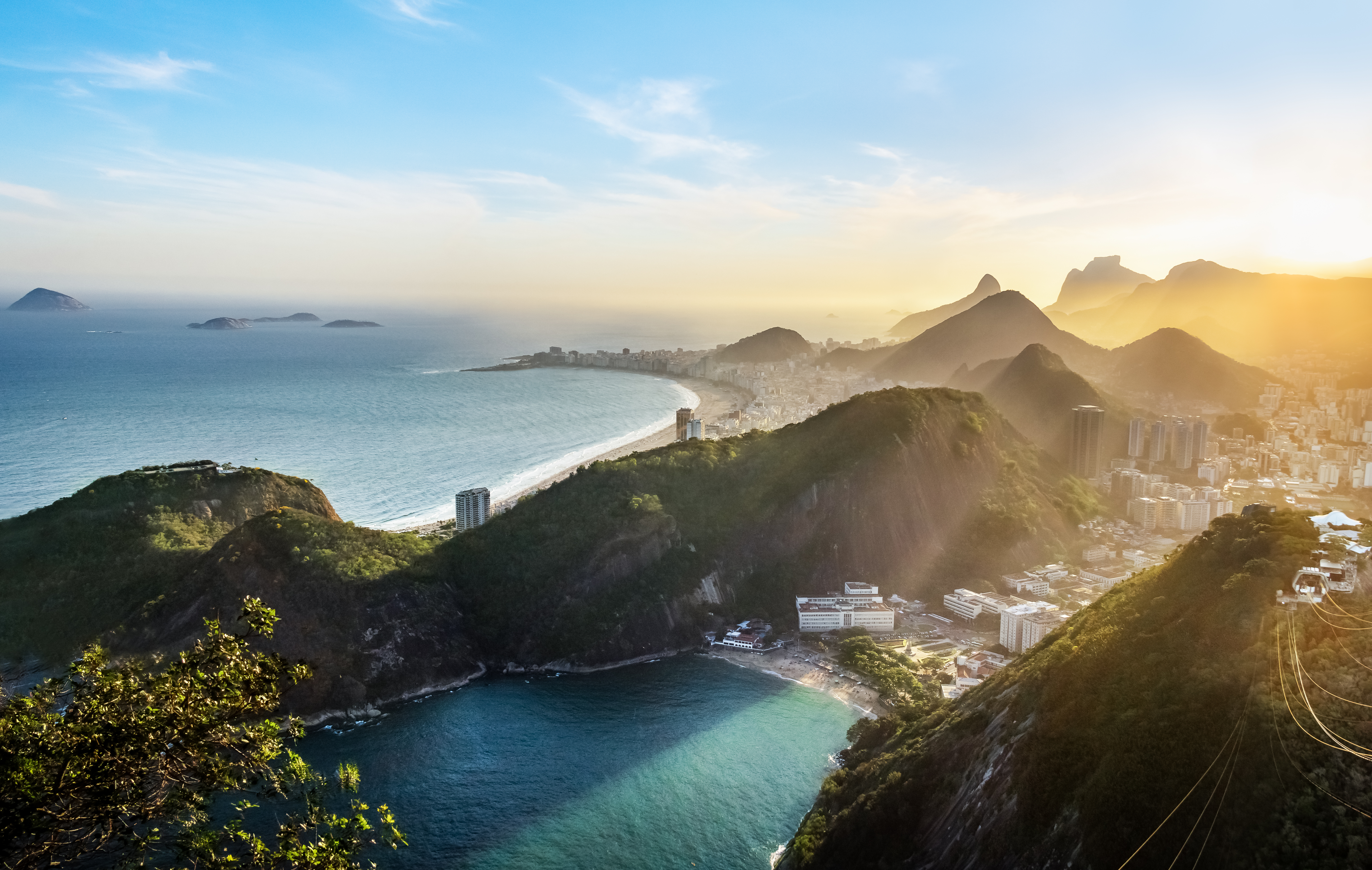Panoramablick auf die Küste von Rio de Janeiro mit Bergen und dem Meer im Sonnenlicht.