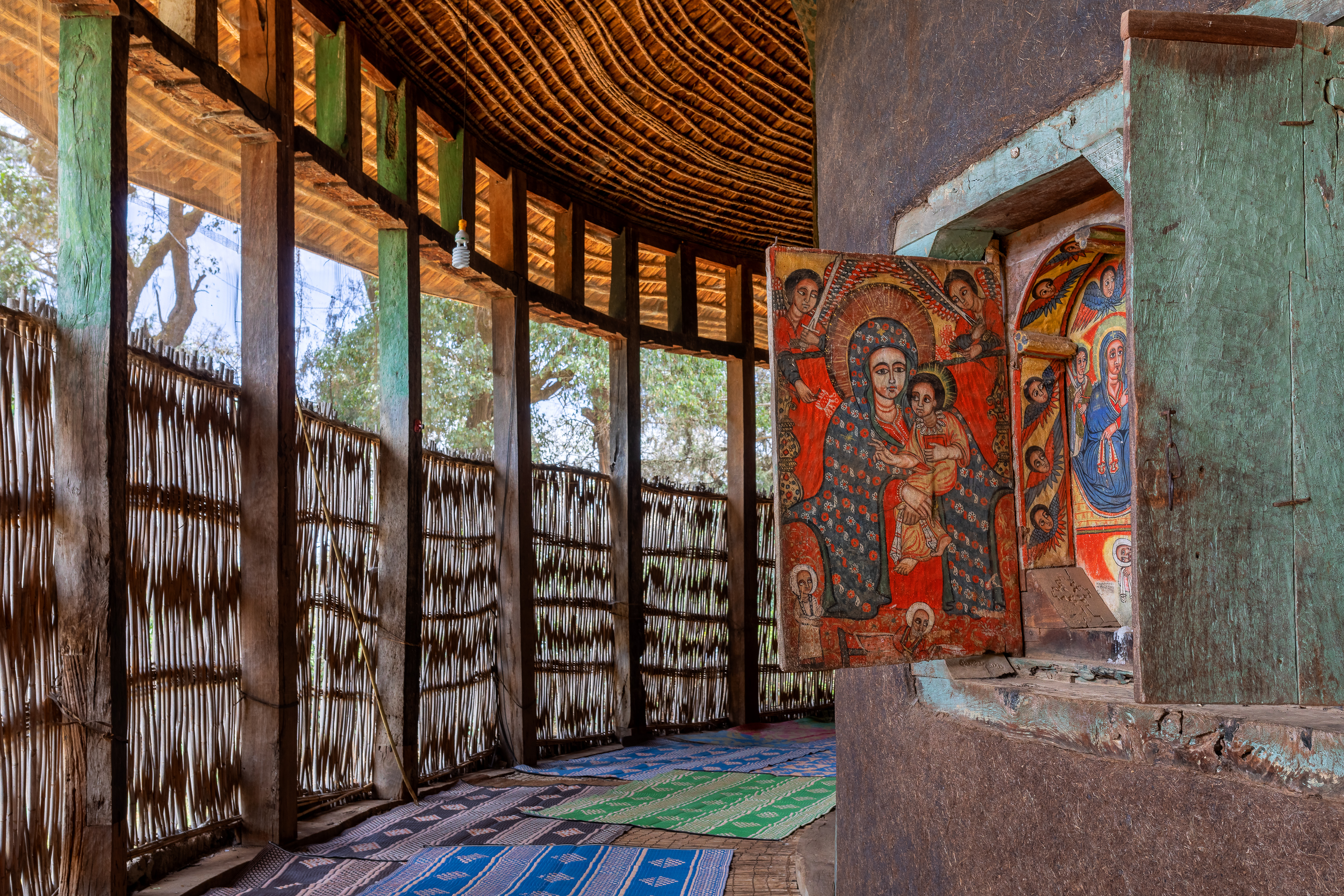 Innenansicht eines traditionellen Gebäudes mit einer Wandmalerei der Jungfrau Maria und einem Kind.