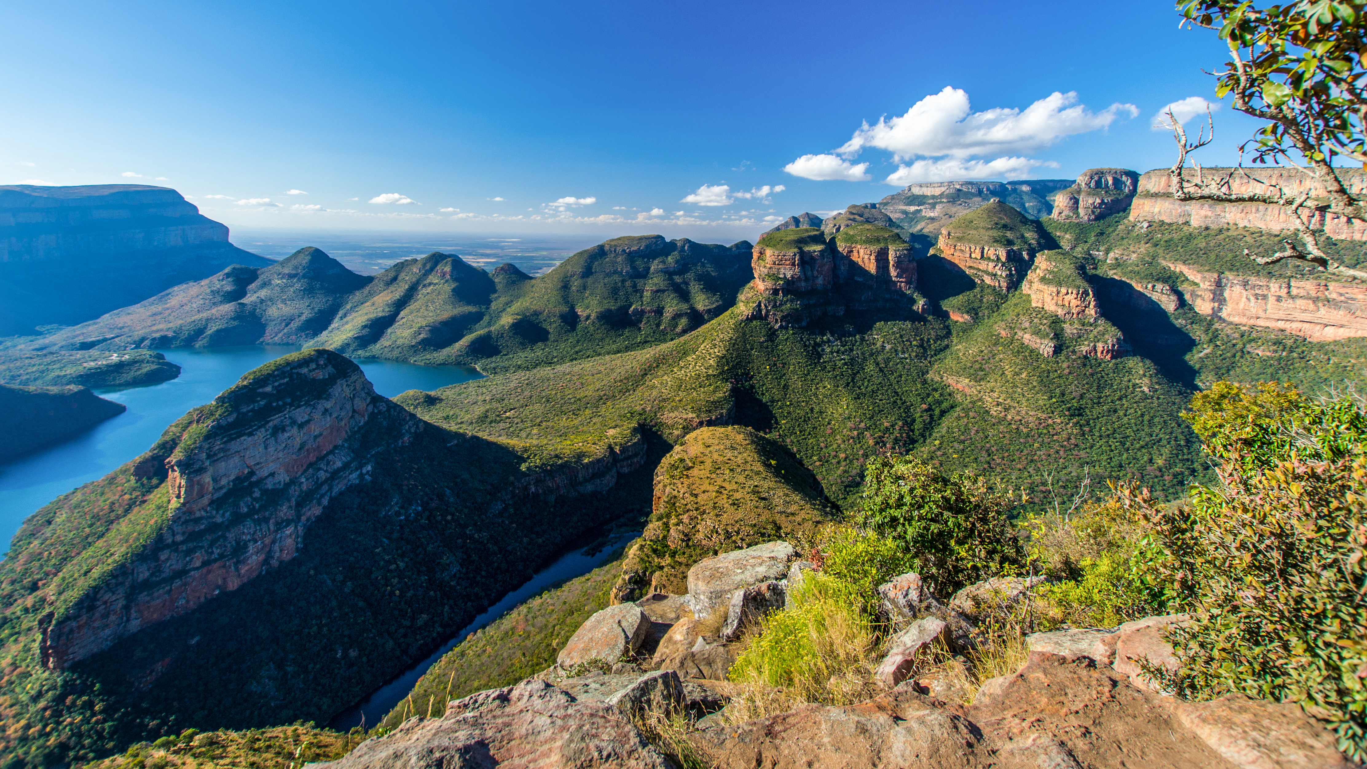 Panoramaansicht der Blyde River Canyon Schlucht in Südafrika mit grünen Hügeln und blauen Gewässern.
