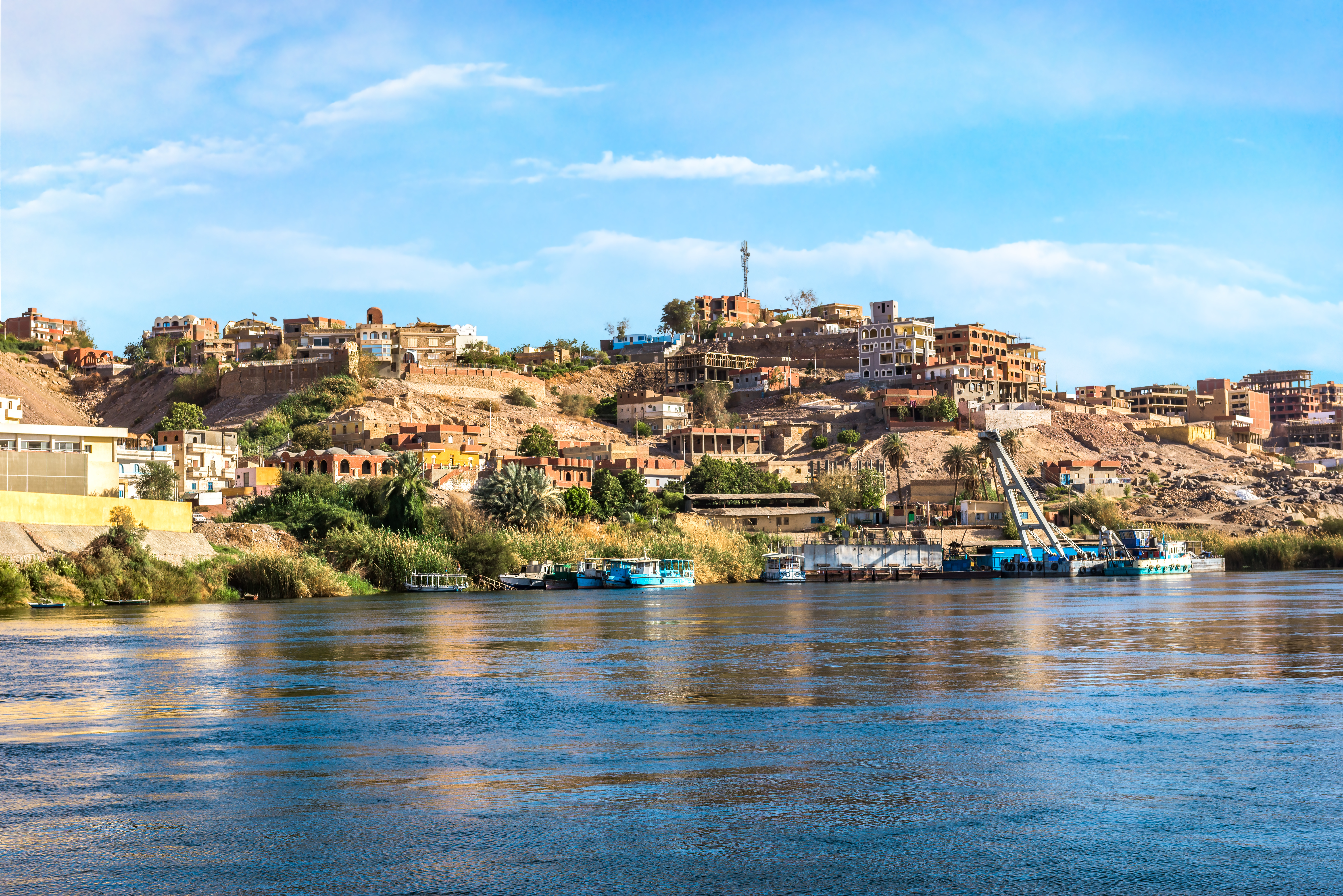 Blick auf eine Küstenlandschaft mit Häusern und Booten am Wasser.