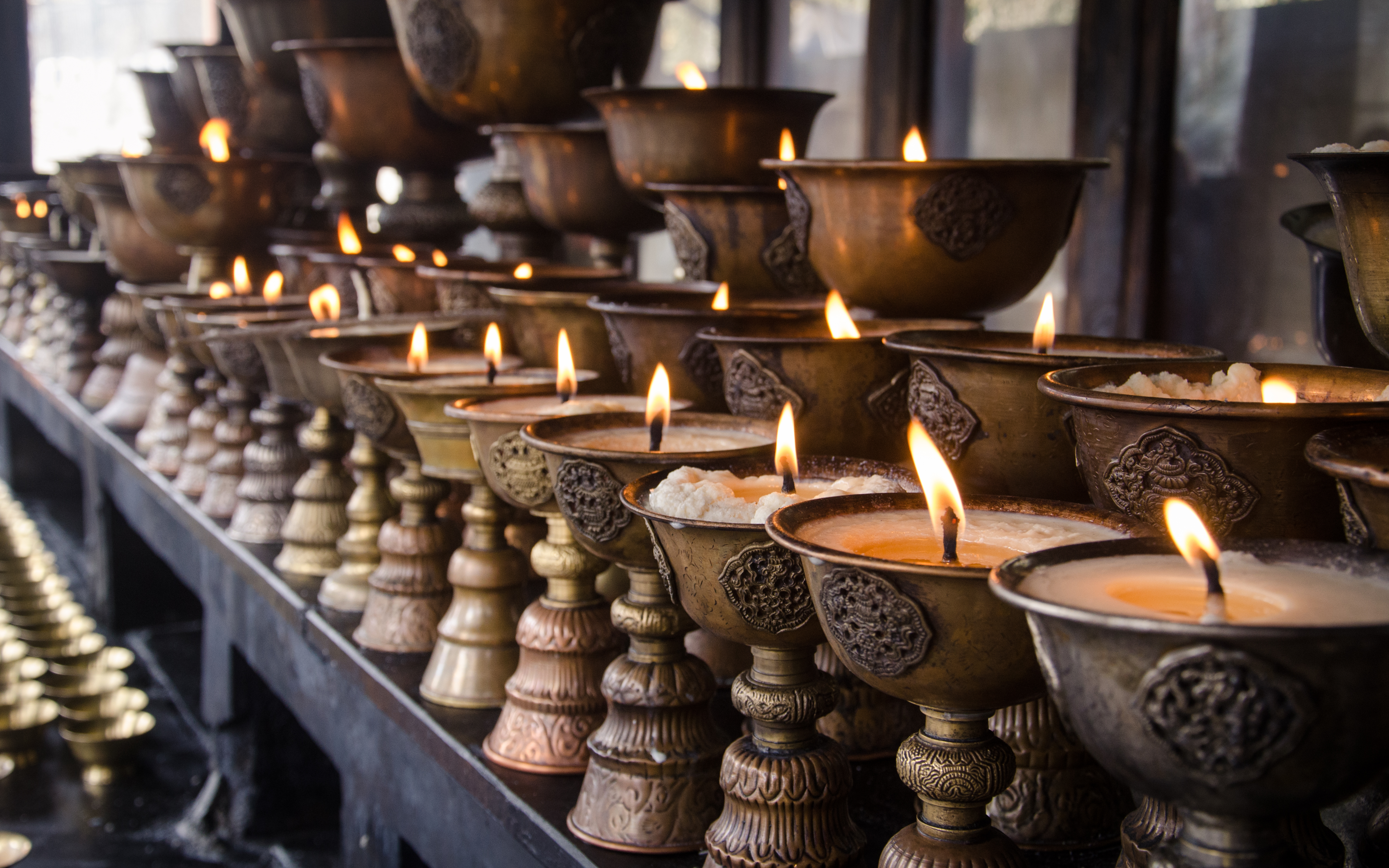 Reihe von traditionellen Öllampen mit brennenden Dochten in dekorativen Halterungen.