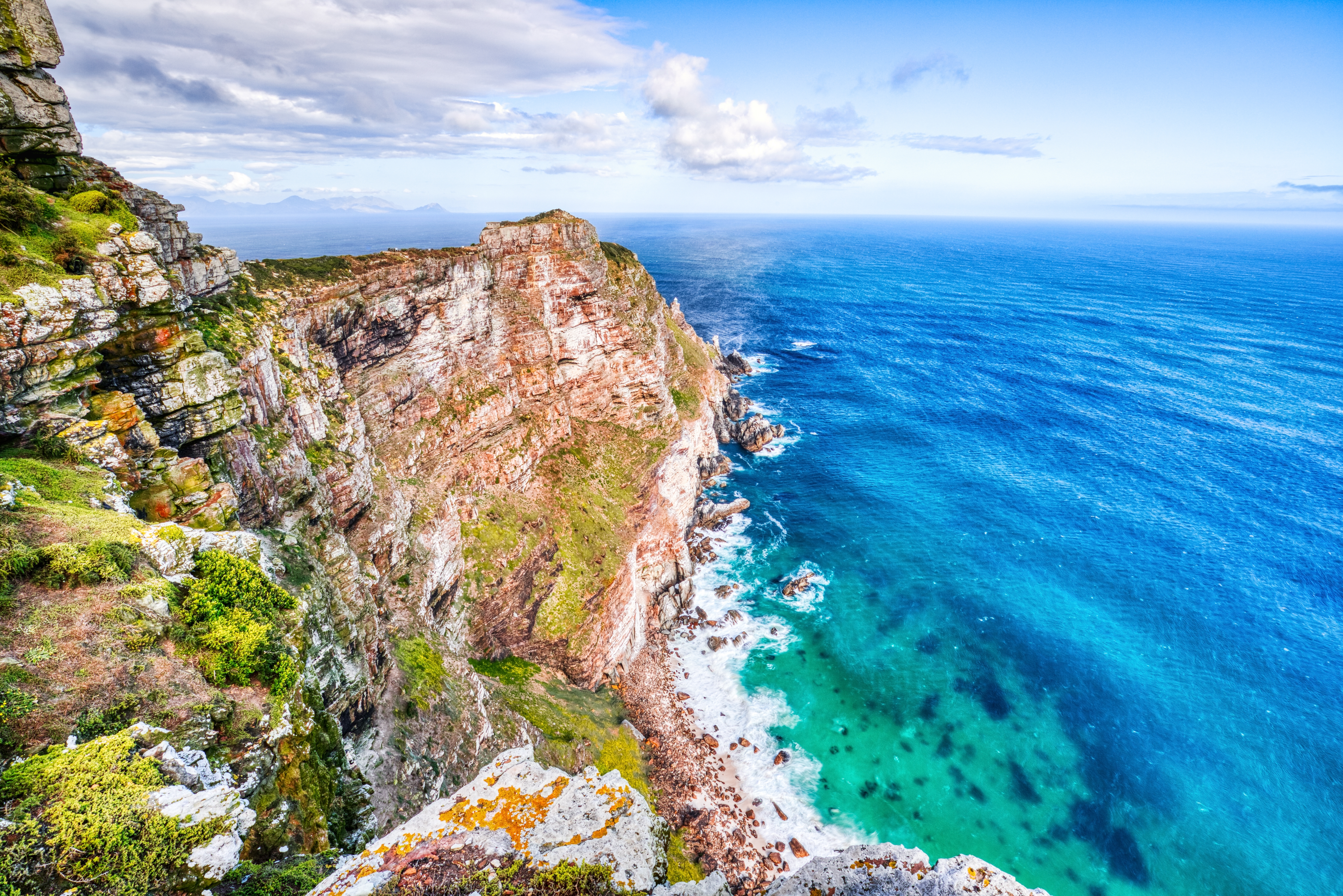 Küstenlandschaft mit steilen Klippen und klarem, blauem Wasser in der Nähe von Kapstadt, Südafrika.