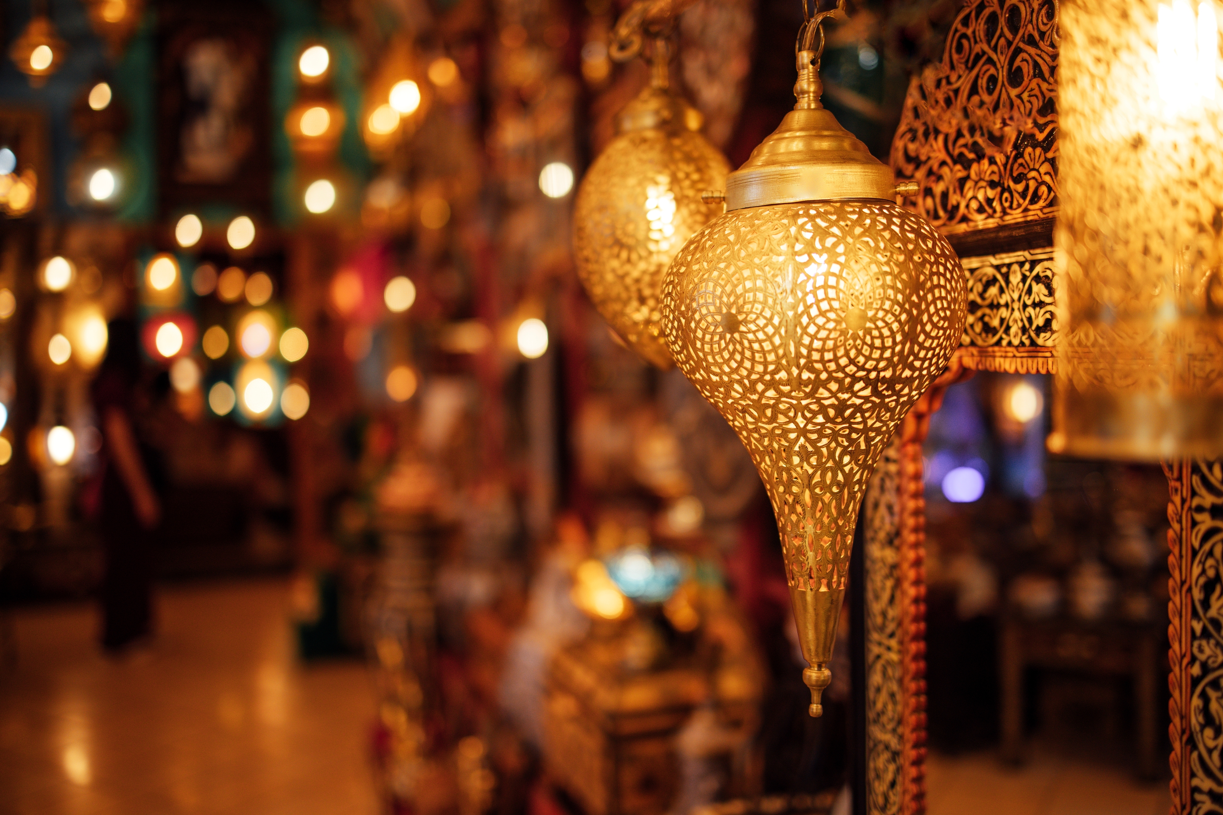 Goldene orientalische Laterne mit filigranem Muster in einem geschäftigen Marktumfeld.