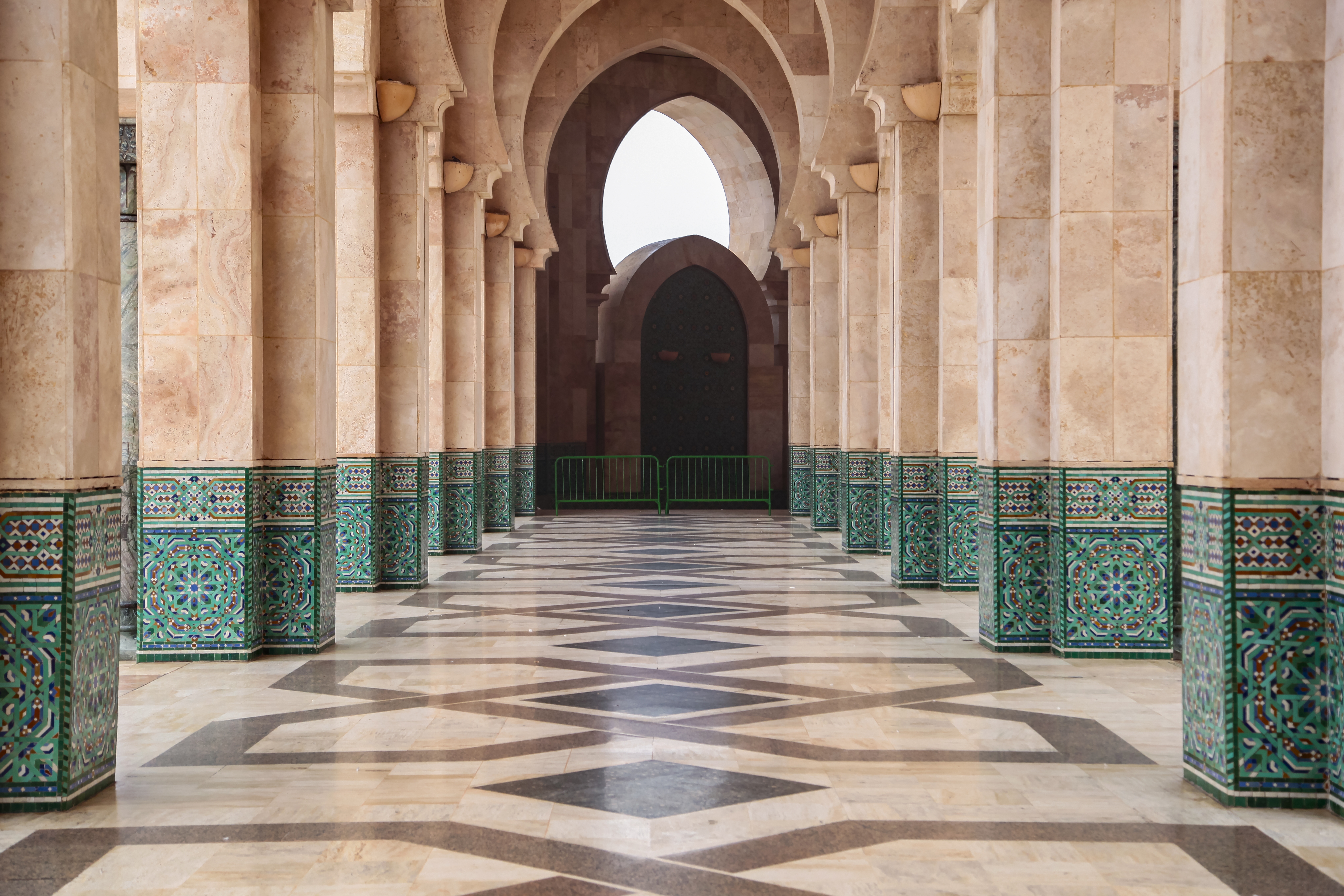 Architektonische Details einer Moschee mit Säulen und Fliesen in grünen und beigen Farbtönen.