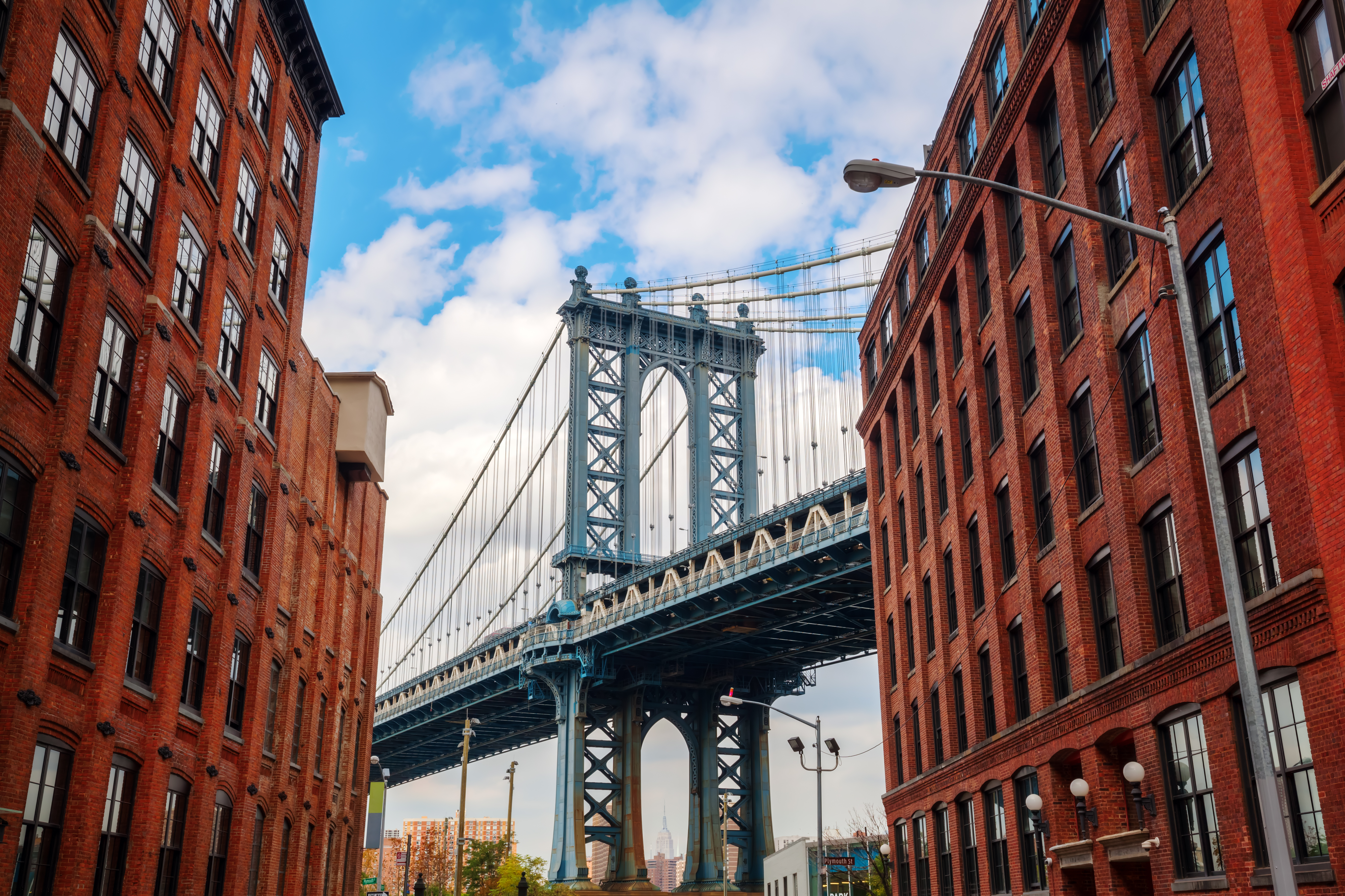 Die Manhattan Bridge, eine Hängebrücke in New York City, sichtbar zwischen Ziegelgebäuden.
