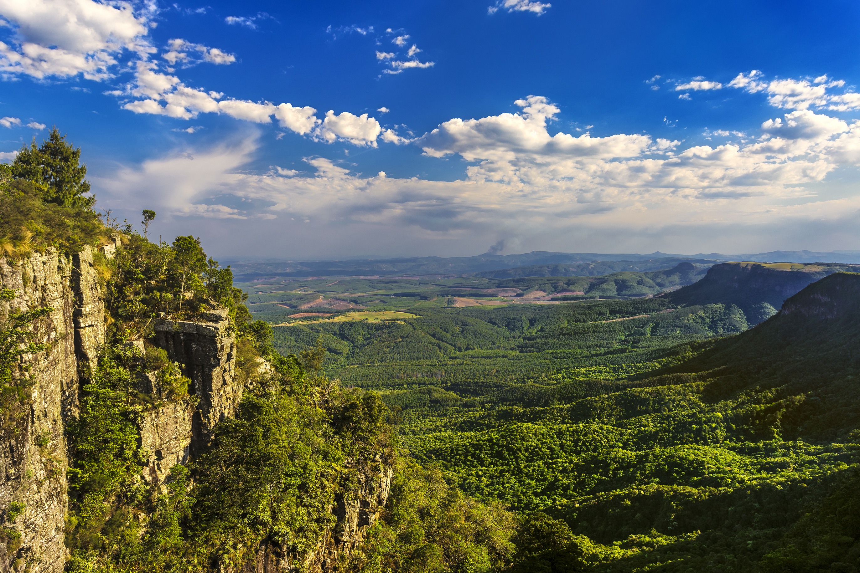 Blick auf eine grüne Landschaft mit Bergen und Wolken am Himmel.