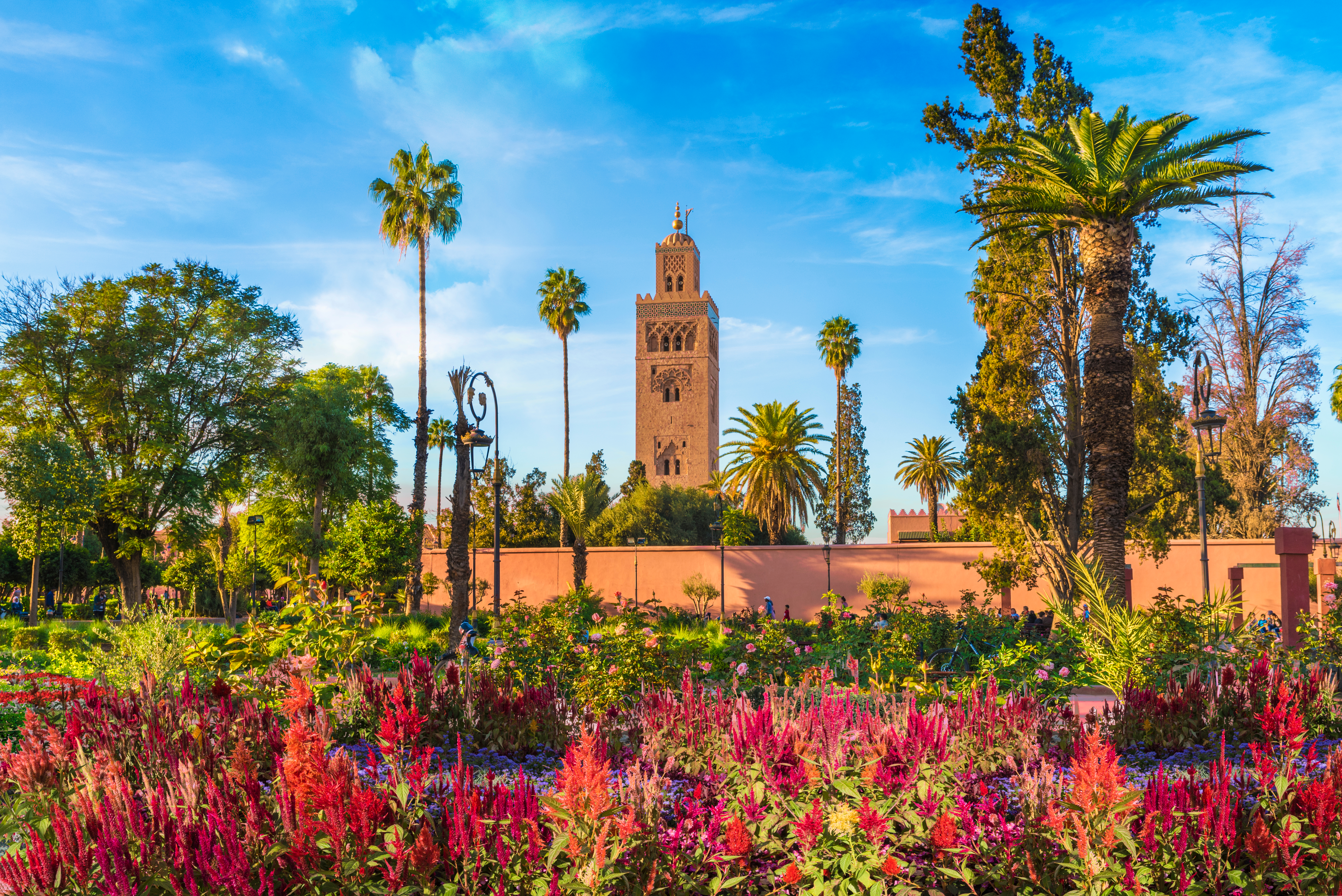 Die Koutoubia-Moschee in Marrakesch, umgeben von bunten Blumen und Palmen.